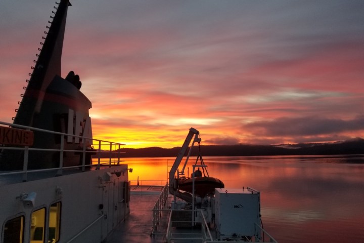 a large ship in a body of water with a sunset in the background