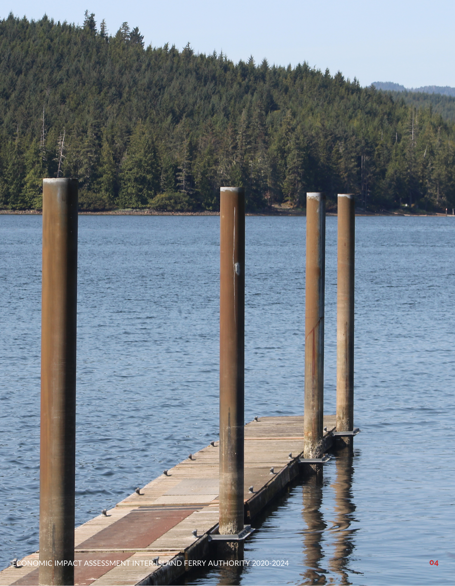 Dock extending into a calm lake surrounded by forested hills under a clear sky.