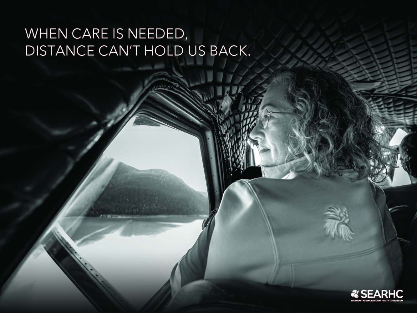 Woman in a plane looking out window at landscape; text: 'When care is needed, distance can’t hold us back.'