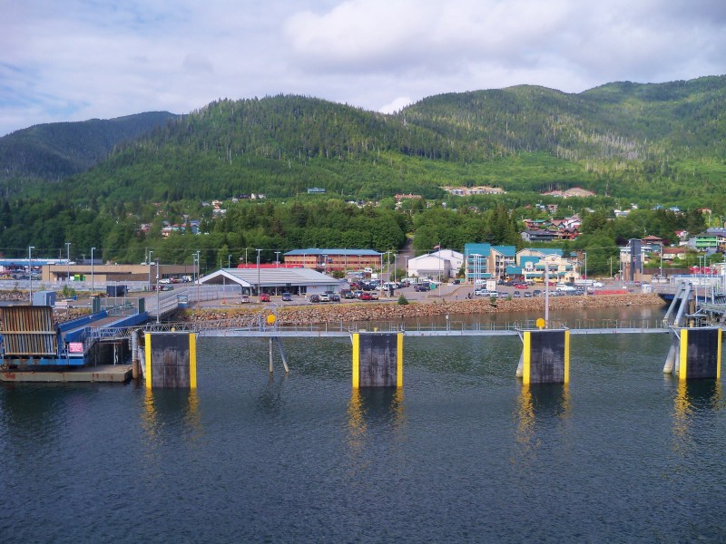 Waterfront town with forested hills and cloudy sky in the background.