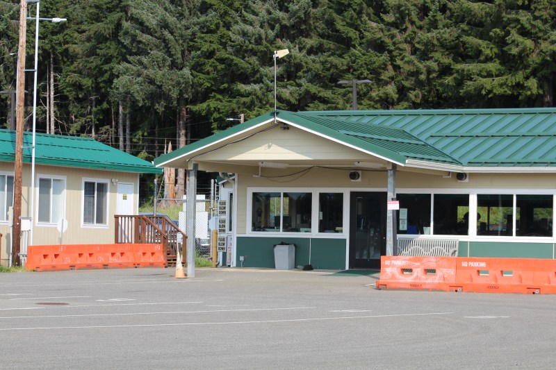 Building with green roof, orange barriers, surrounded by trees.