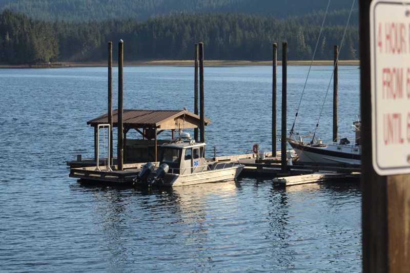 Small boat docked at a calm lake with mountains in the background.